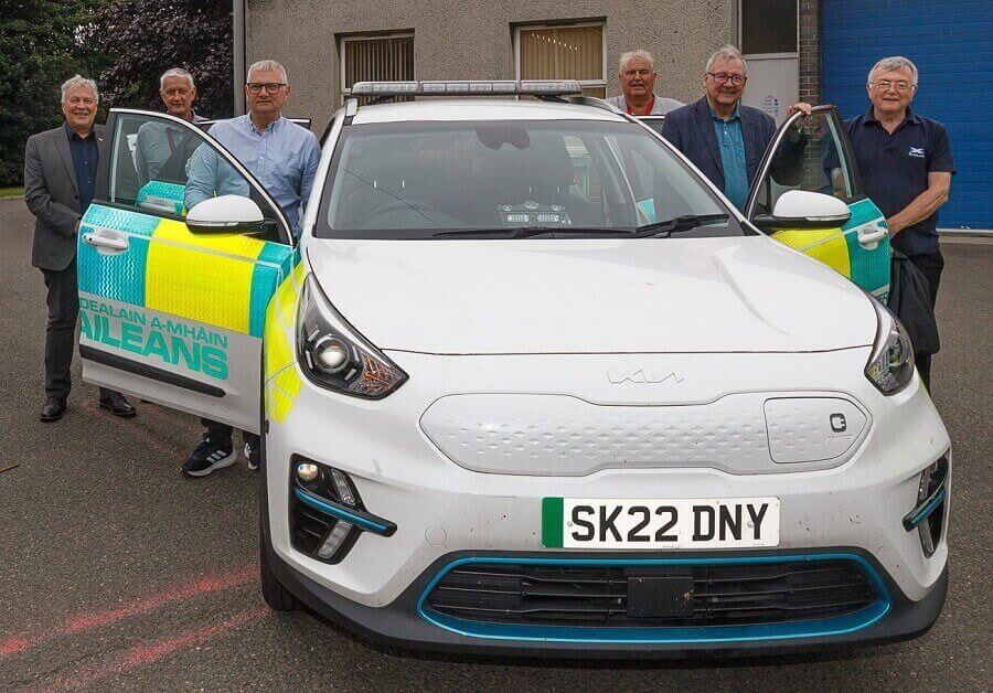 A group of people standing next to an ambulance car