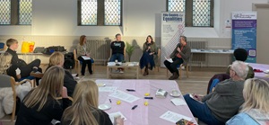 Group of people sitting in a hall 'round a table