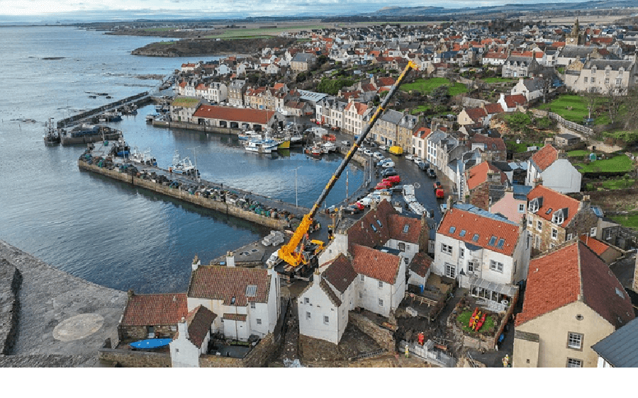 A crane in position between houses on the Pittenweem coast working to repair the coastal defence.