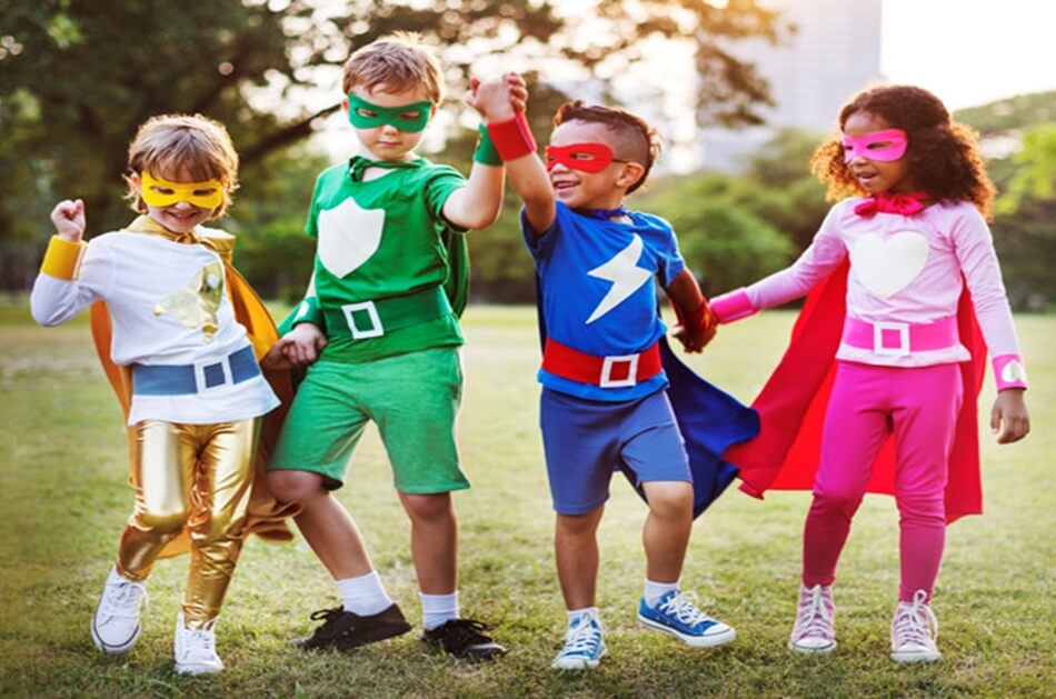 A group of young children around four years old, dressed in brightly coloured superhero costumes and posing with their arms up