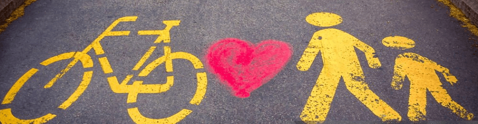 Image of yellow line markings on a road of a bicycle and two stick figures, with a red love heart between them.