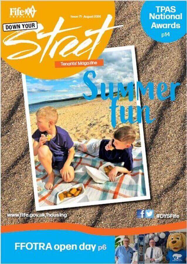 Front cover of the DYS August edition 2024, with children sitting on a picnic blanket on a beach