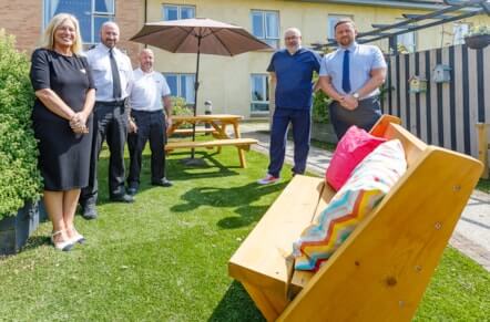 People from the Good Neighbour project standing next to benches made by those in the care of HMP Perth.