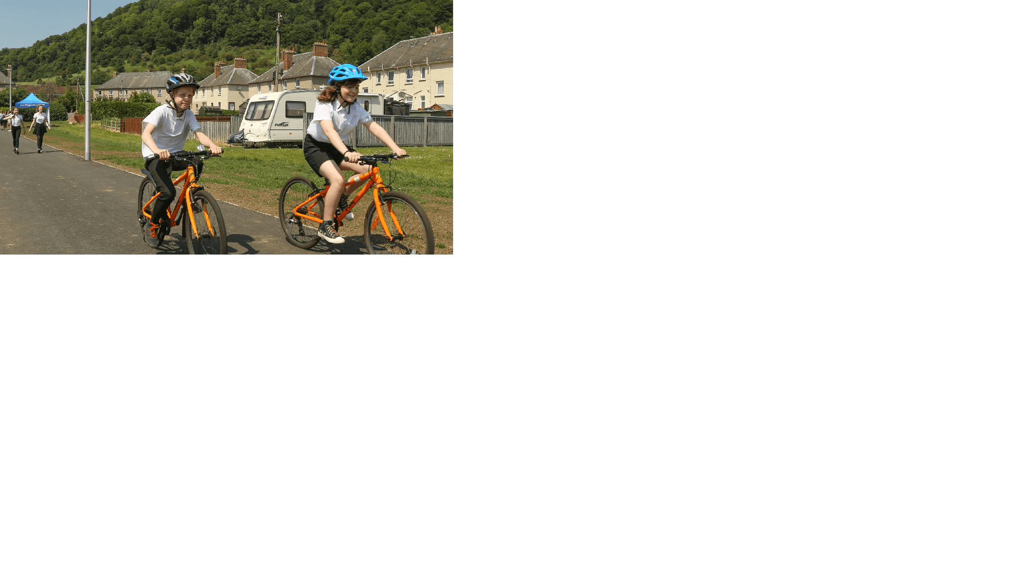 Two school children cycling to school on an active travel multi-use path.